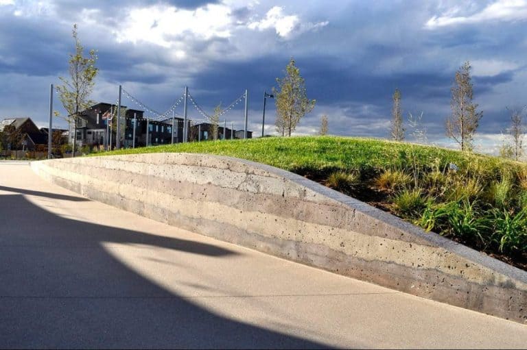 Outdoor walkway next to sedimentary wall with different colored concrete.