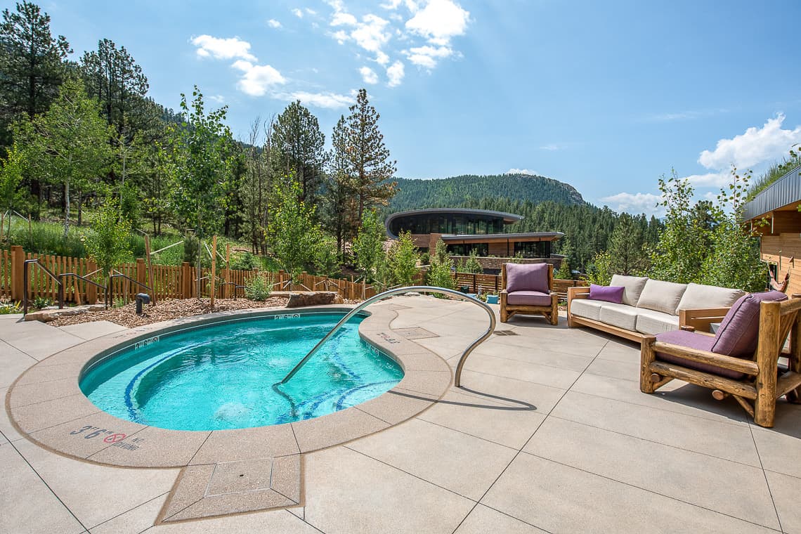Jacuzzi set within a sandscape concrete area, accompanied by outdoor furniture nearby.