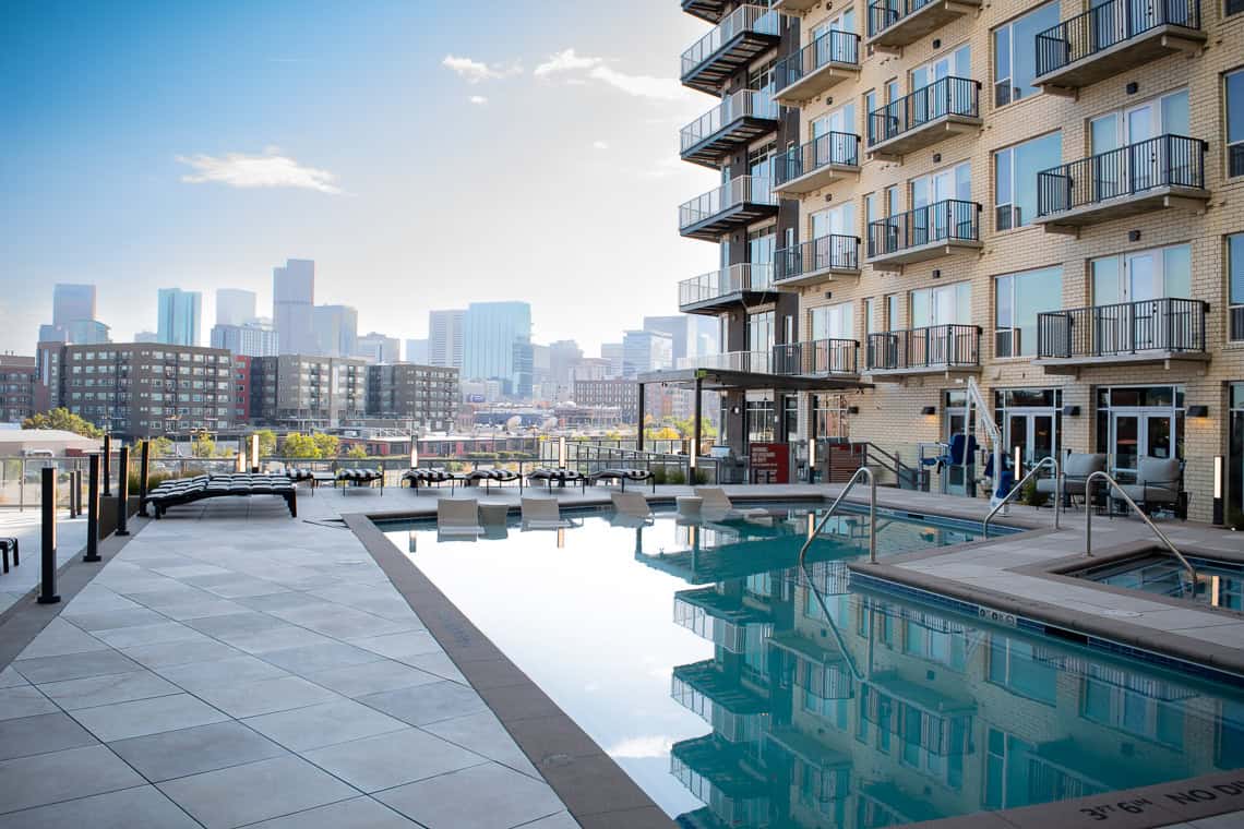 Two pools, one smaller than the other, surrounded by pedestal pavers and lounge chairs all around.